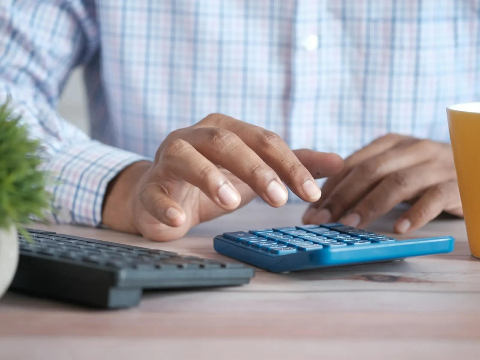 Manos usando una calculadora junto a un teclado sobre el escritorio
