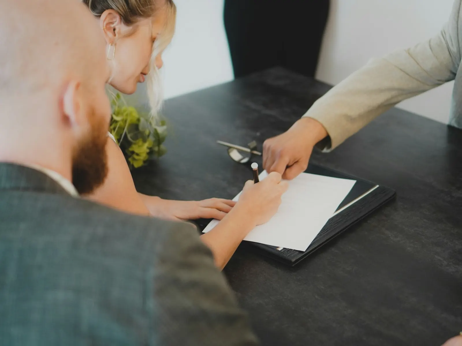 Pareja firmando la escritura de compraventa de una vivienda junto a su abogado